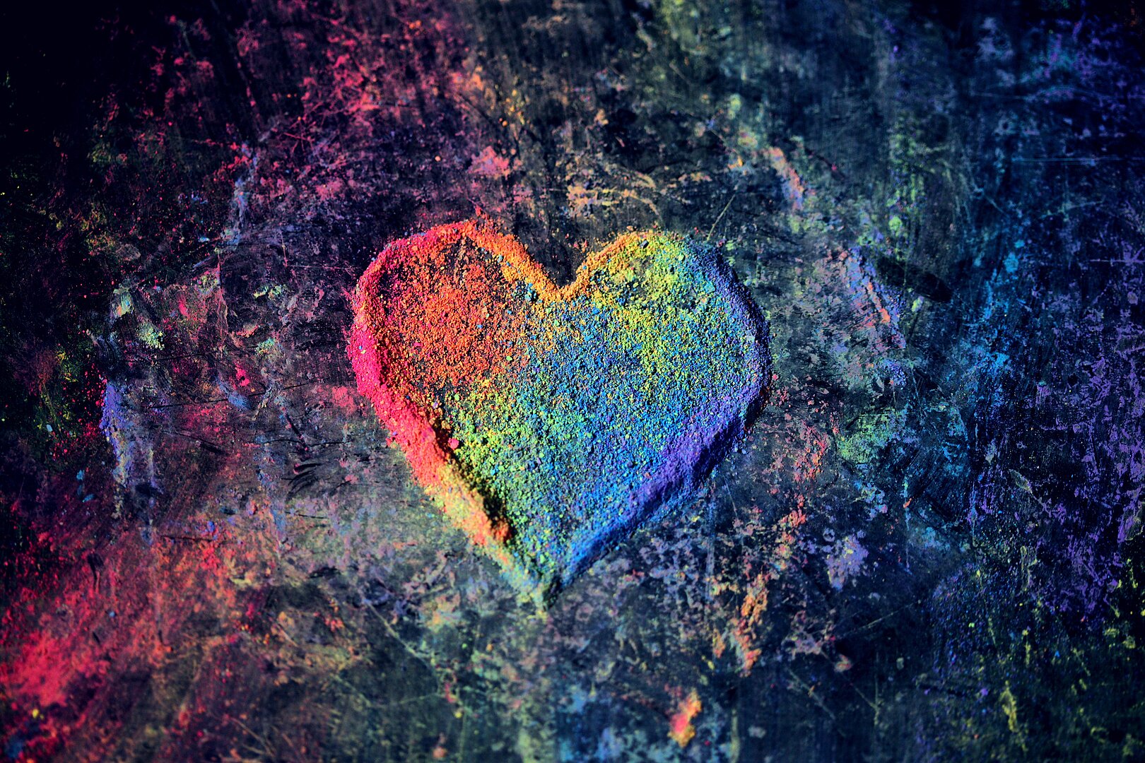 Bild mit Herz in bunten Farben auf dunklem Hintergrund mit Farbstaub